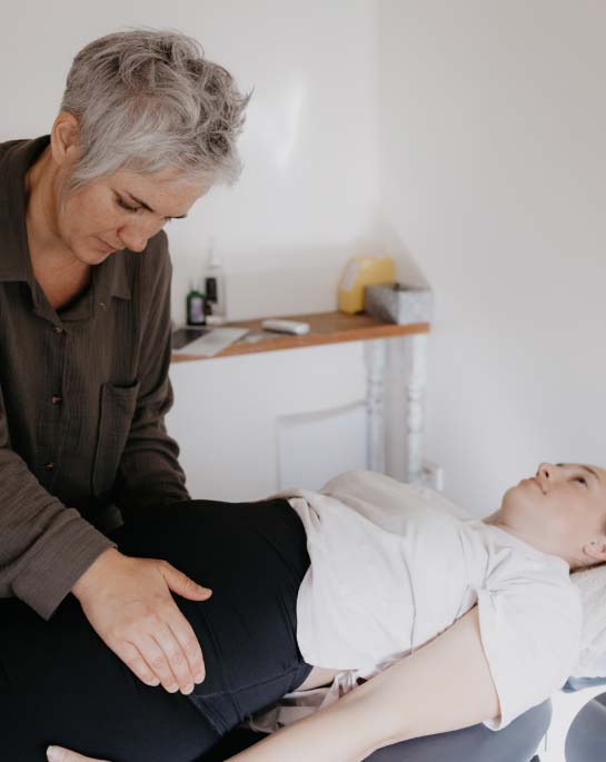 Chiropractor gently assessing a pregnant woman with her hands.
